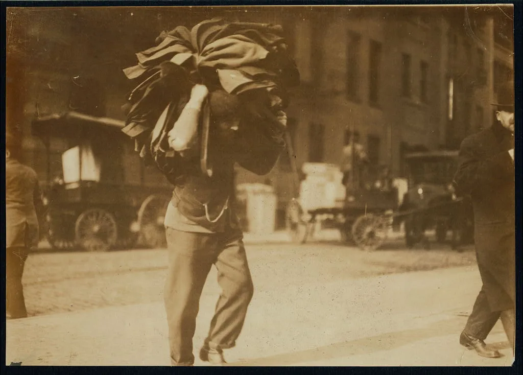 Man carrying bundle of garments. Bleecker Street, N.Y. Location: New…, New York (State), 1912