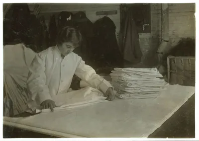 15-year old girl folding coats in Bonanno Laundry.  Location: Boston,…, Massachusetts, 1917